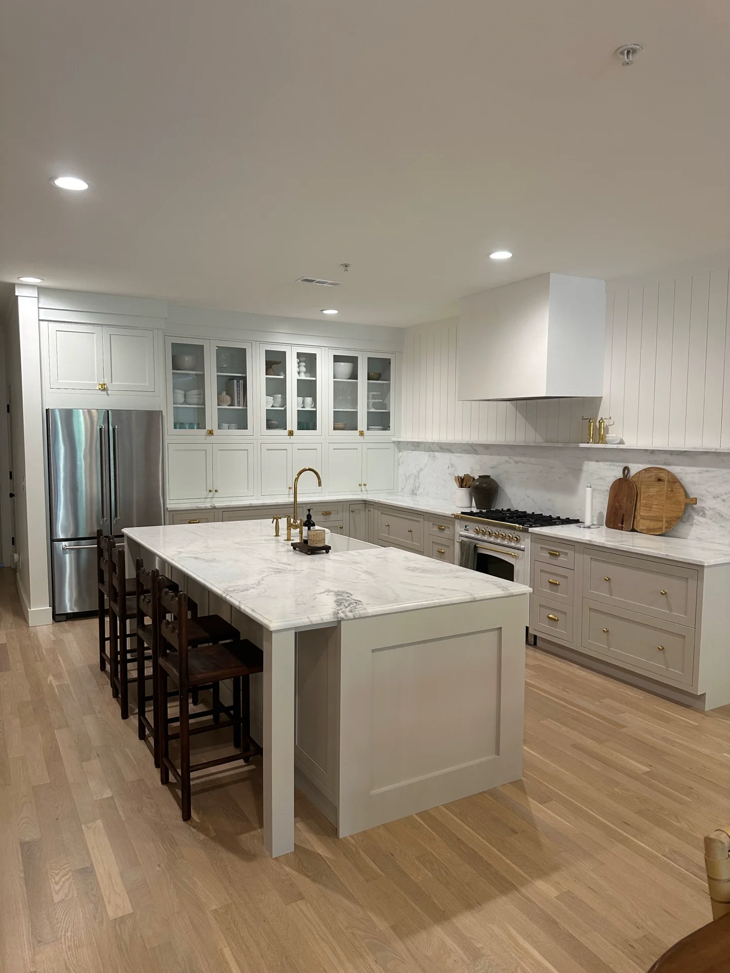 Light greige Magnolia kitchen with a marble island and brass hardware