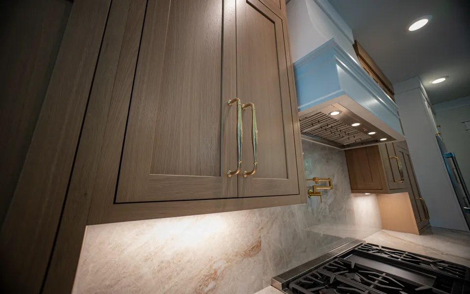 Warm oak cabinetry with brass hardware and integrated lighting